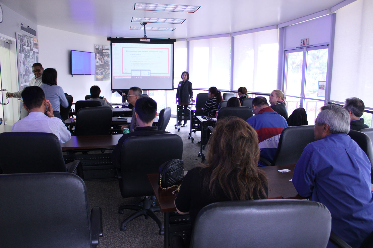 Classroom of business people listening to Francine Chiu give a teaching on financial freedom.